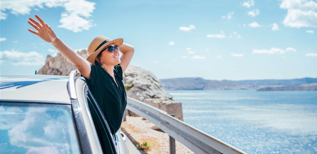 Woman leaning out of car window, beautiful weather, vacation